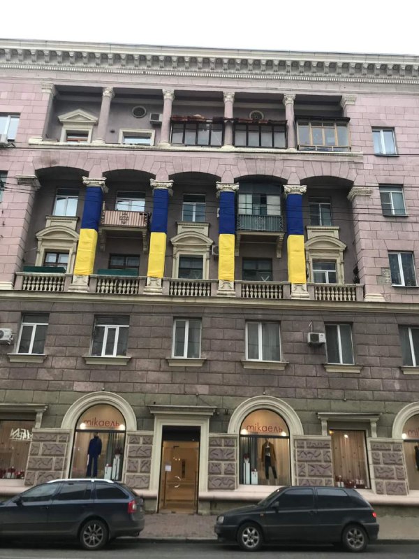 Цікава декомунізація.

Під жовто-блакитними прапорами  приховано серпи з молотами та зірки, якими прикрашені колони будівлі.